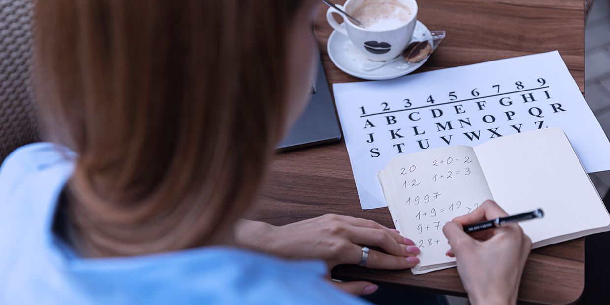 A young woman sitting at a desk, doing numerology sums to calculate her life path number.