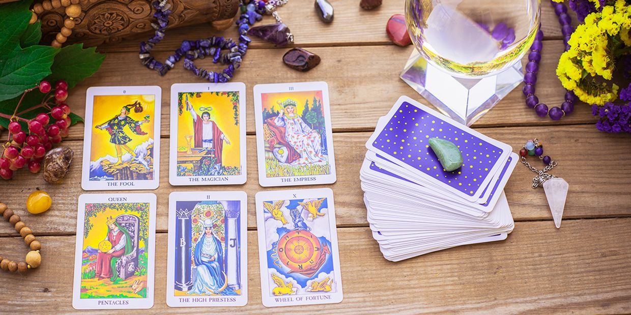 A selection of tarot cards situated on a wooden table. The cards include The Fool and The Magician.