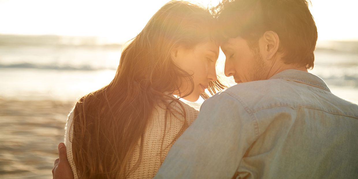 Young couple embracing on a beach, evoking love and connection.