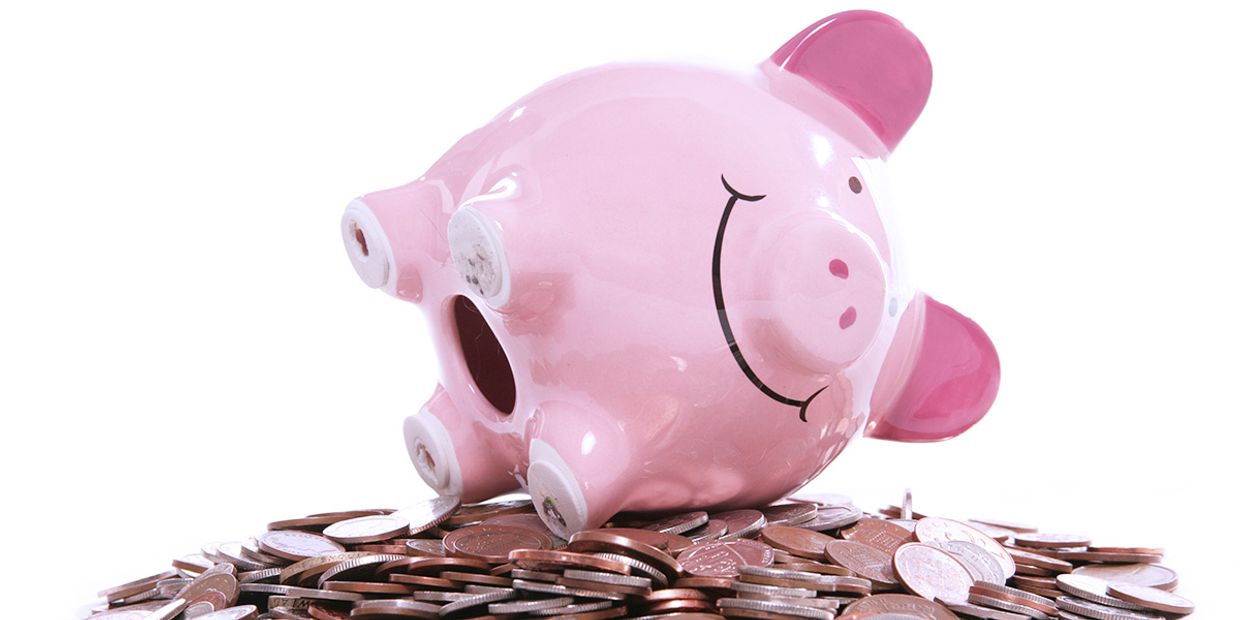 A picture of a pink piggy bank on it's side, on top of British coins.