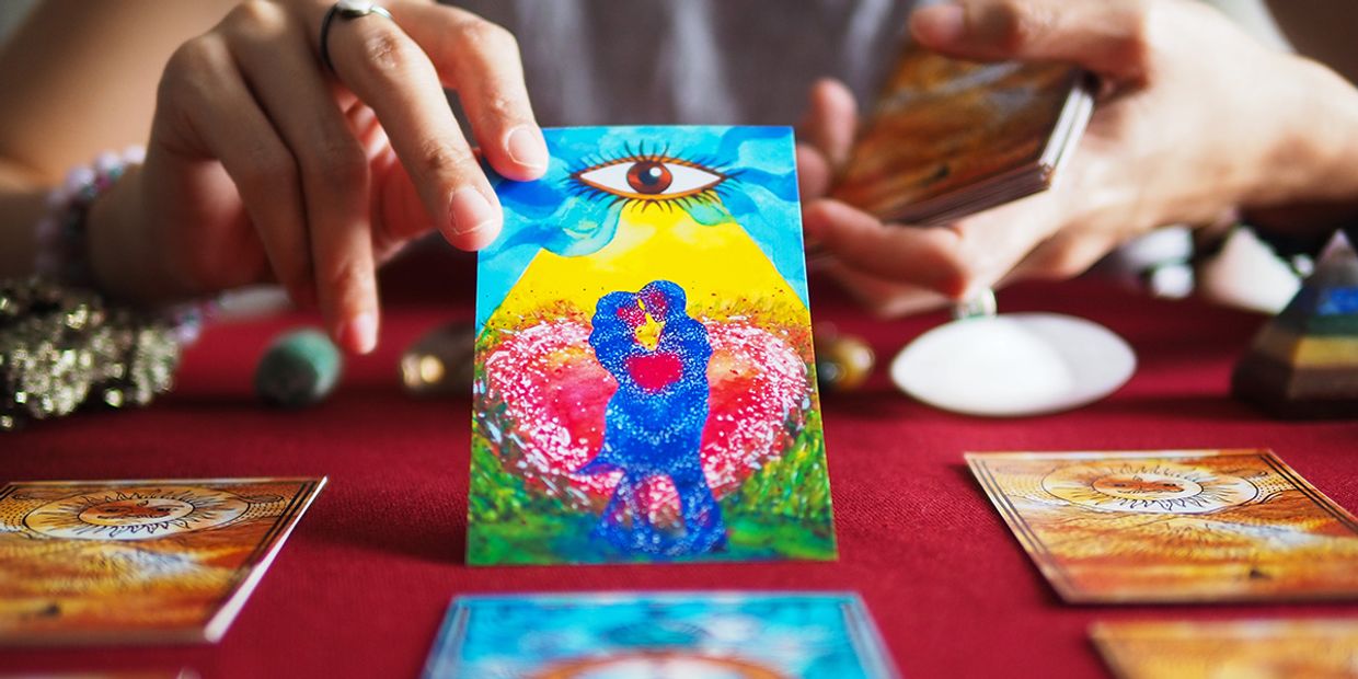 Illustration of a psychic showing a colourful love-themed tarot card with an image of a couple embracing each other and a soulmate and relationship insight, intuitive energy.