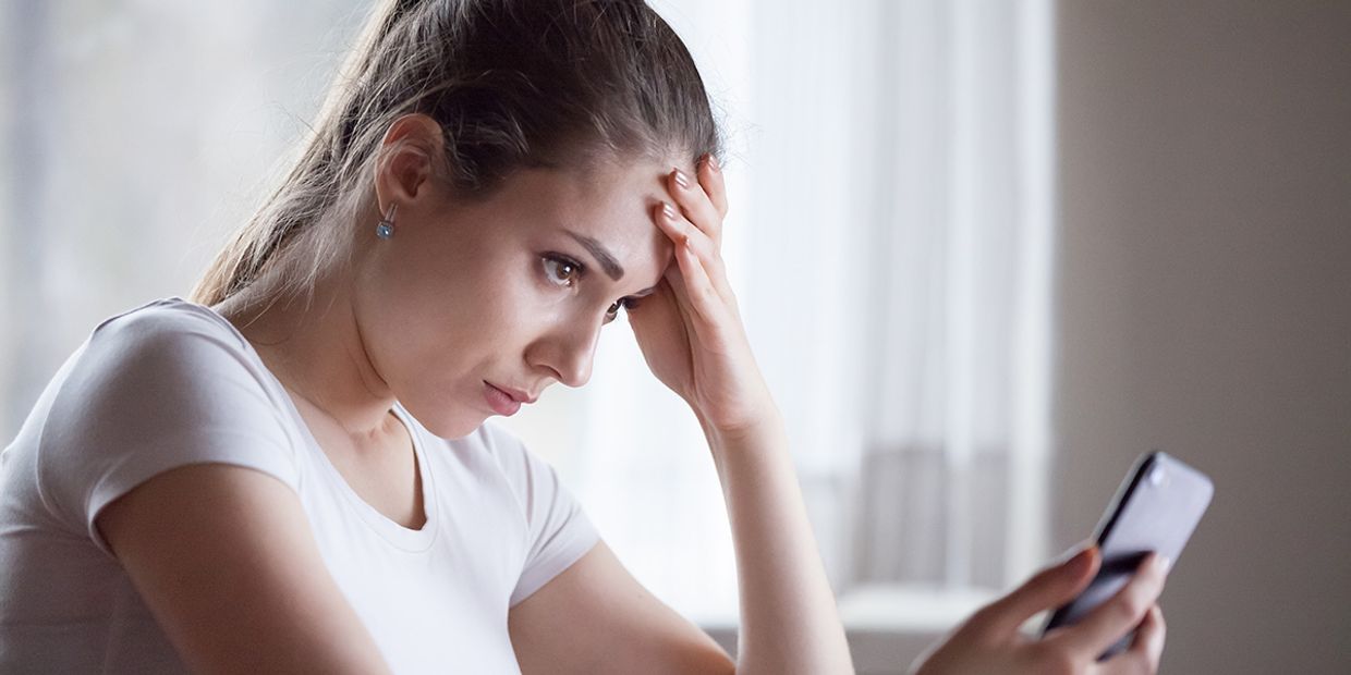A jealous Gemini woman, looking at texts on her mobile phone.