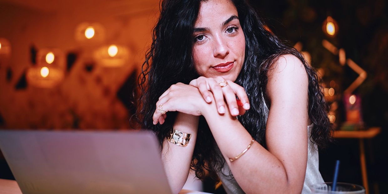 A corporate looking lady, sitting by her laptop, looking serious.