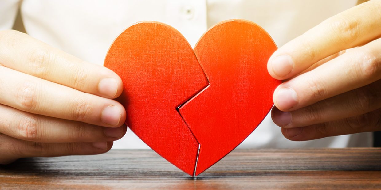 A person holding a broken heart symbol, depicting love and emotional struggles.