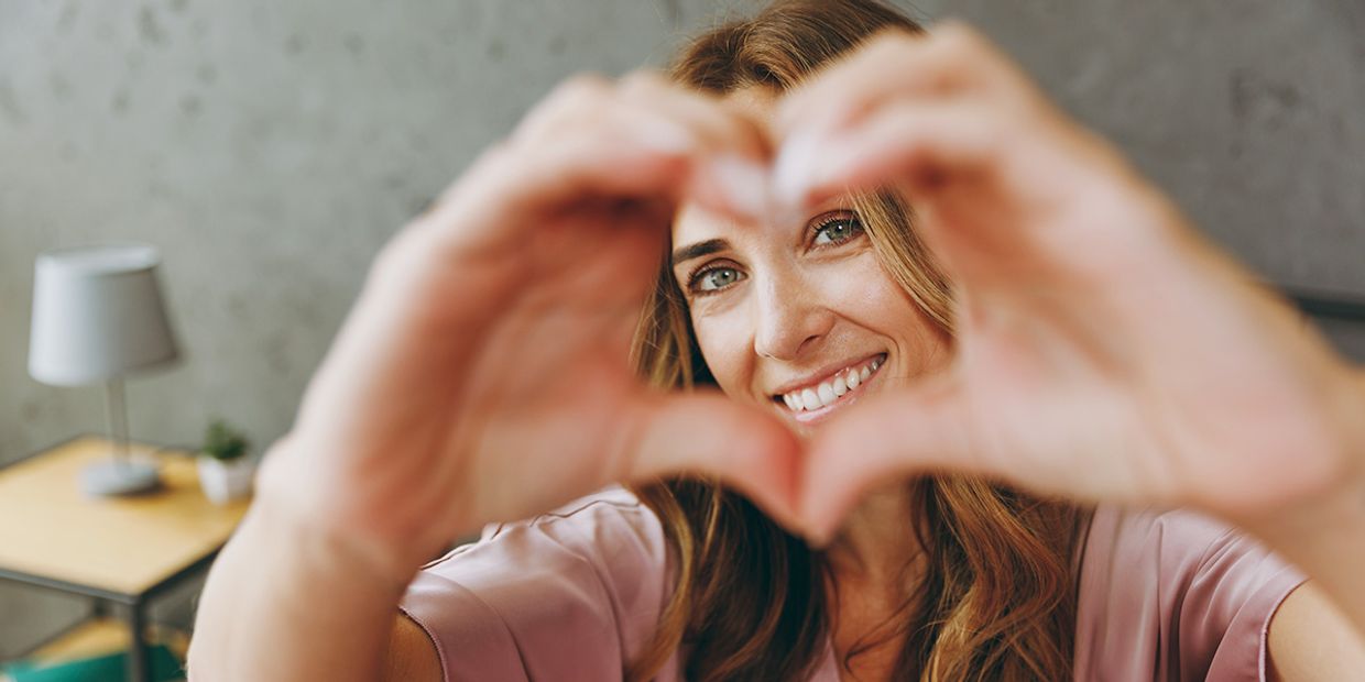 King of Cups Tarot Meaning - A single woman, making a heart shape with her hands.