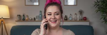 A female psychic reader with pink hair, on the phone, giving a psychic reading.