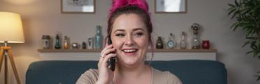 A female psychic reader with pink hair, on the phone, giving a psychic reading.