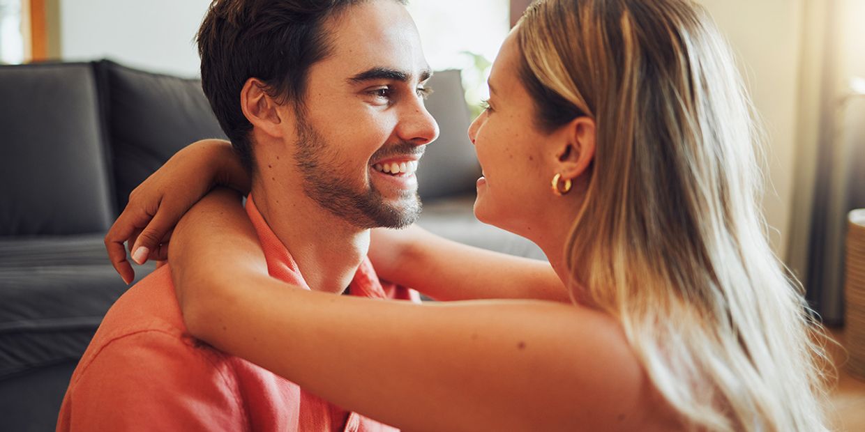 A happy couple, embracing in their living room.