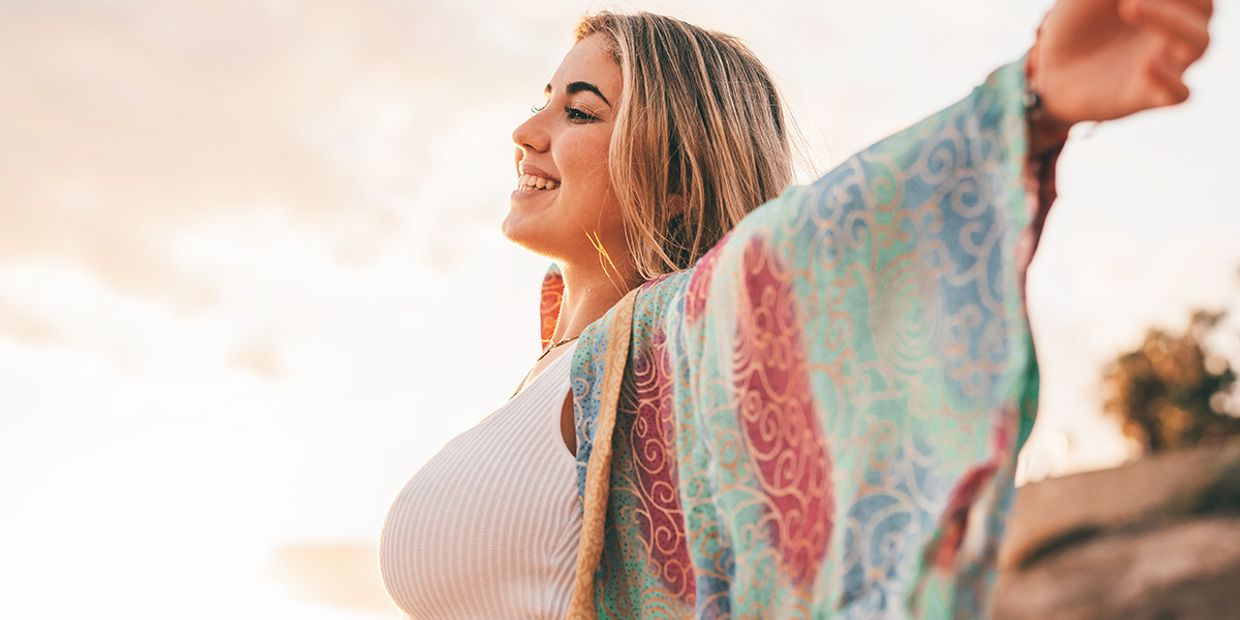 A happy and relaxed lady with her arms outstretched, wearing a shawl.