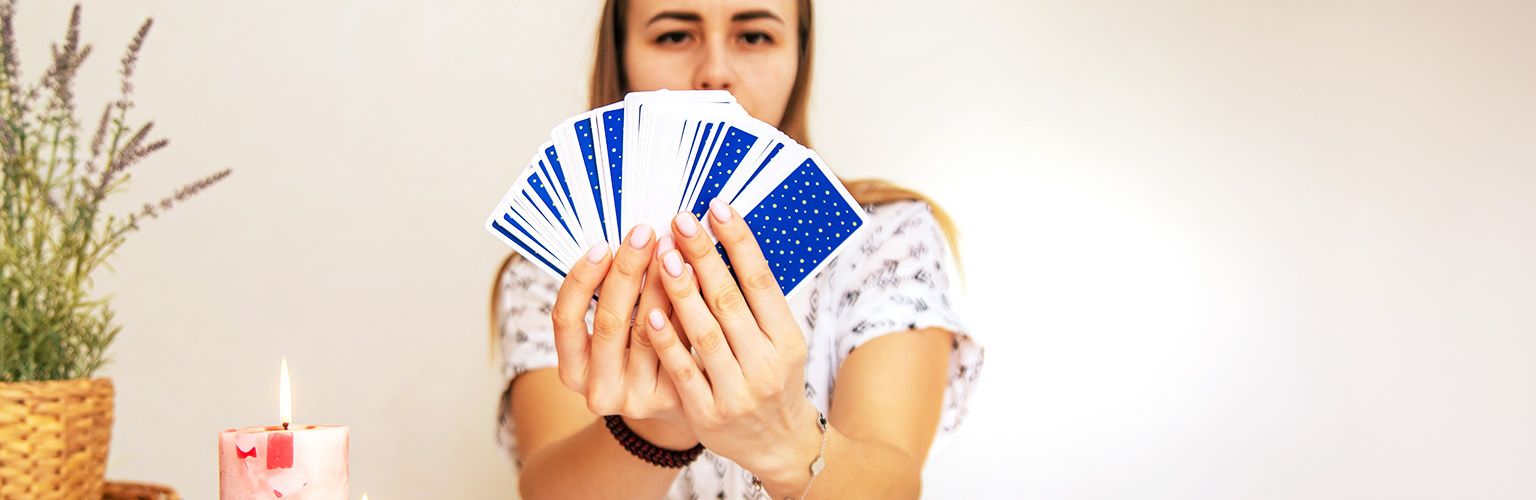 A female tarot reader holding a spread of tarot cards in front of her.