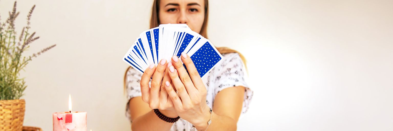 A female tarot reader holding a spread of tarot cards in front of her.