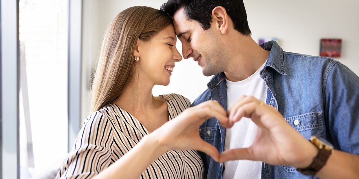 Couple forming a heart with their hands, symbolising love and connection.