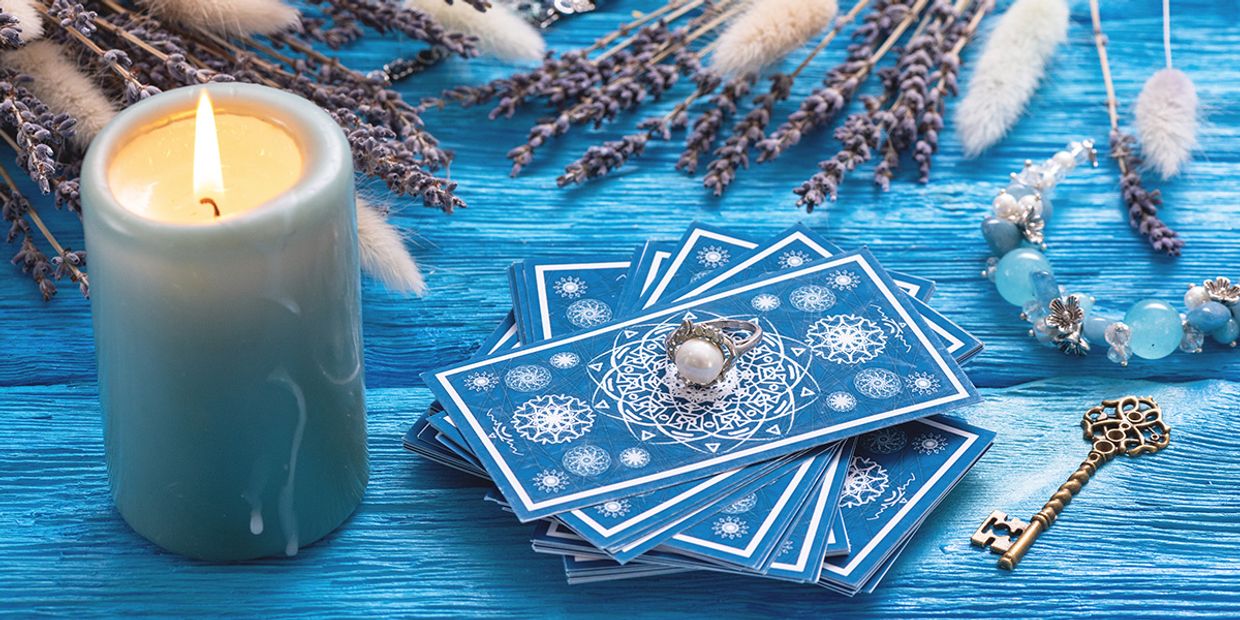 What Is a Clairvoyant? A deck of tarot cards with a single candle next to them.
