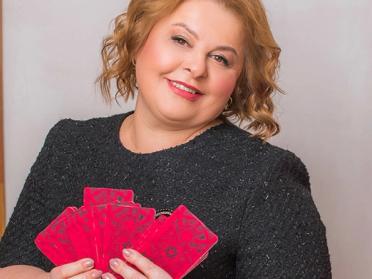 A middle aged female psychic reader, holding her tarot cards in her living room.
