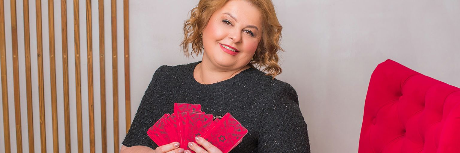 A middle aged female psychic reader, holding her tarot cards in her living room.