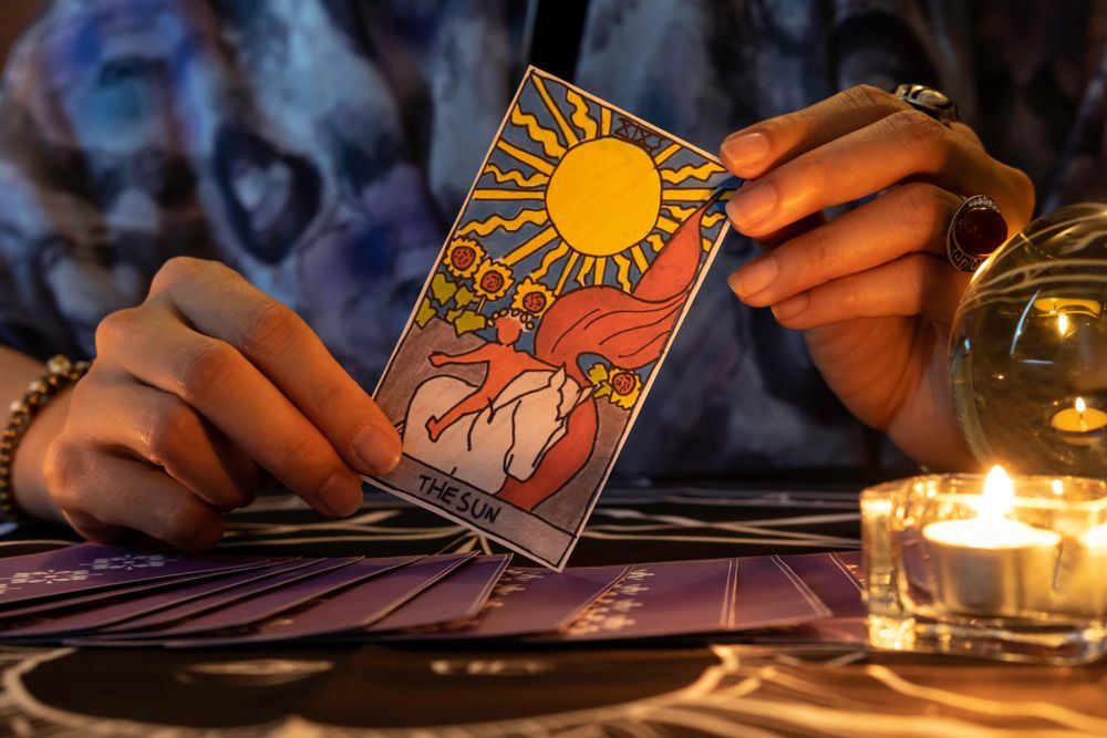 A tarot card reader holding The Sun tarot card