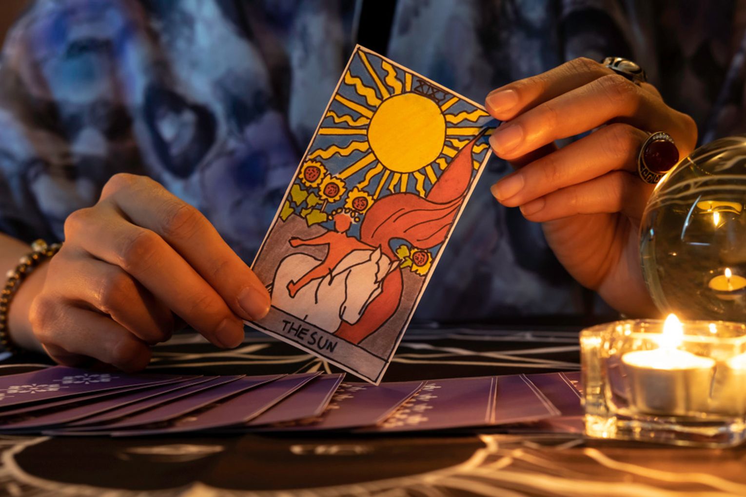 A tarot card reader holding The Sun tarot card
