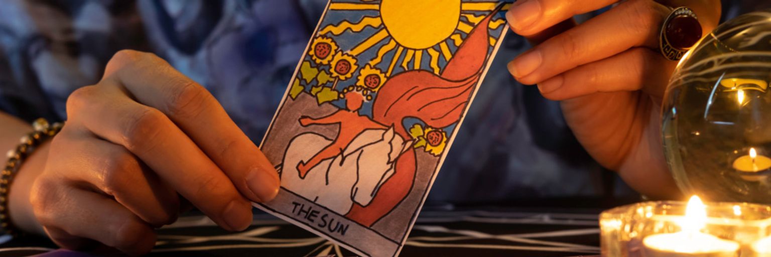 A tarot card reader holding The Sun tarot card