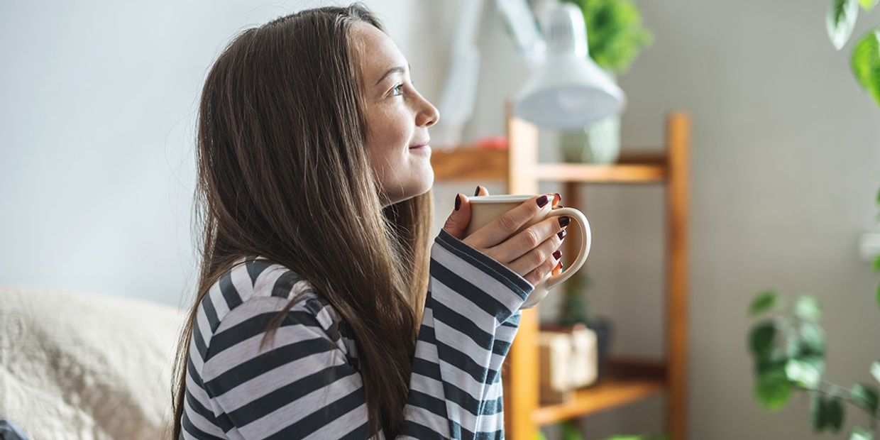 A relaxed woman drinking coffee in her living room.