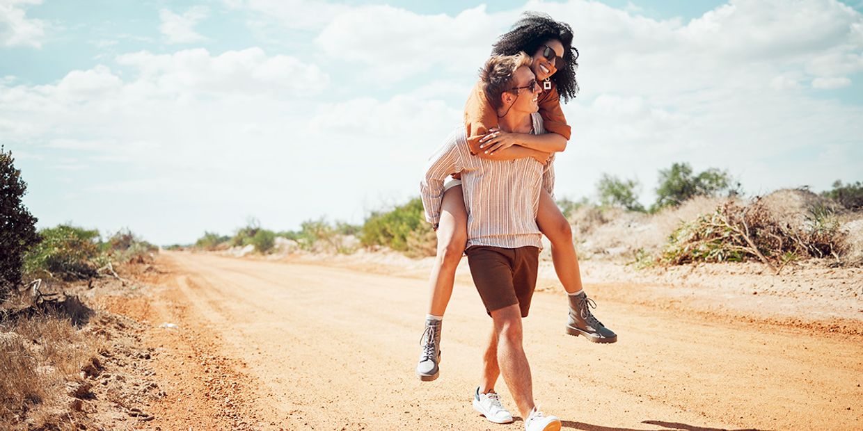 Couple joyfully embracing on a sunny dirt path, symbolising love and connection.