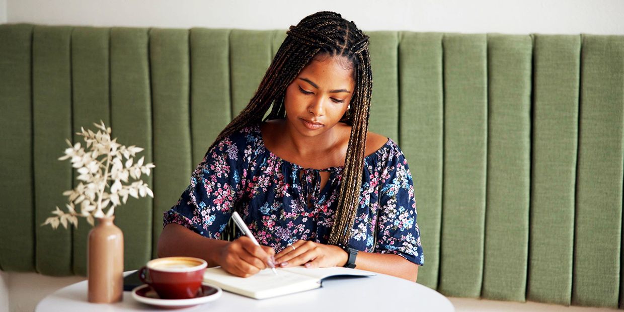 A young woman journalling at a table.