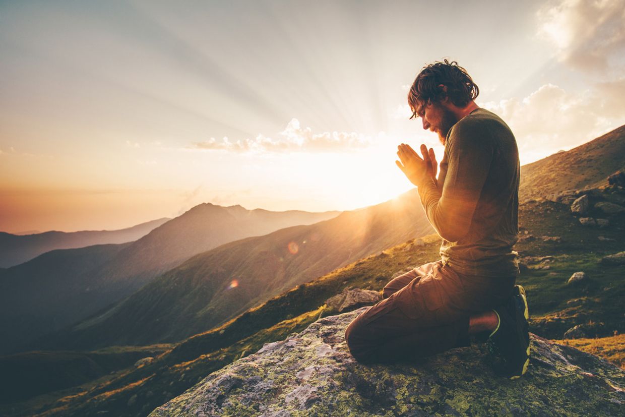 A man praying on a mountain top