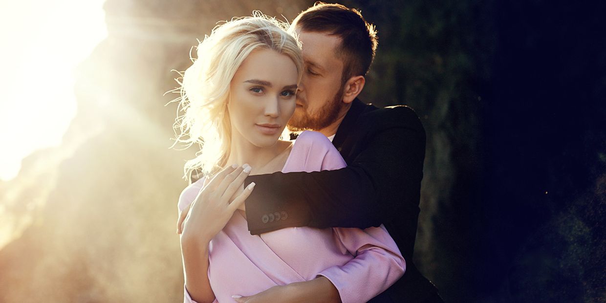 A young couple embracing in the sun, they appear very much in love.