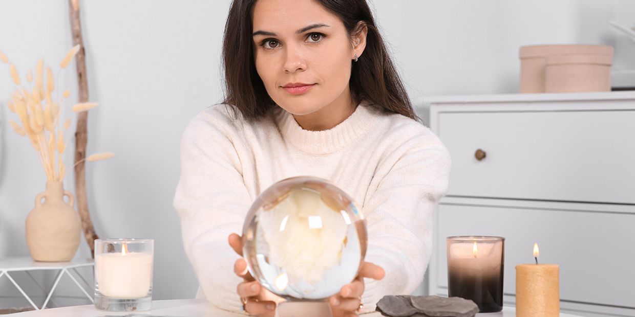 A woman in her 30's with brown hair, holding her psychic crystal ball.