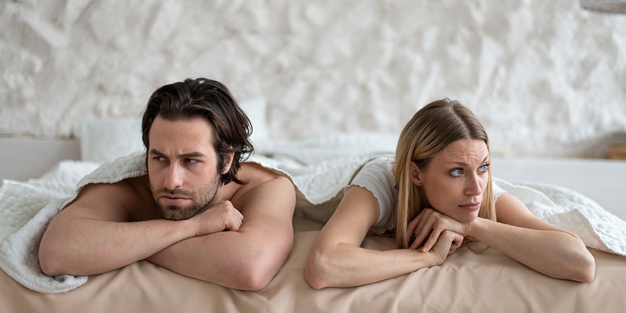 A frustrated young couple lying next to each other.