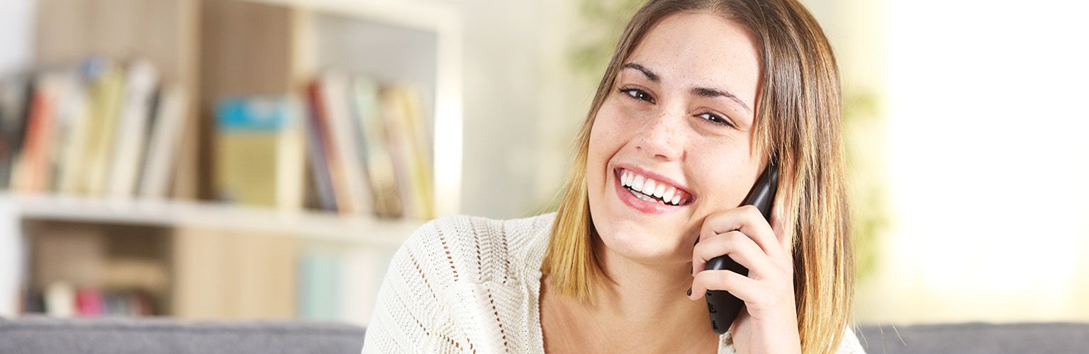 Smiling woman enjoying a phone psychic reading service in the UK.