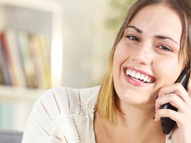 Smiling woman enjoying a phone psychic reading service in the UK.