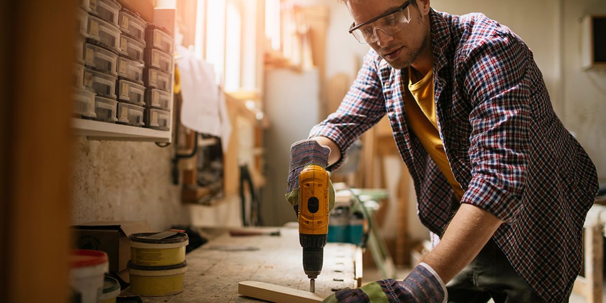 A hard working man, making something out of wood in his workshop.