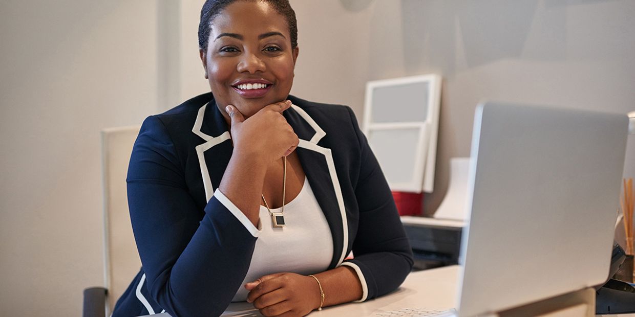 A woman sitting at her office desk, happy to be at work.