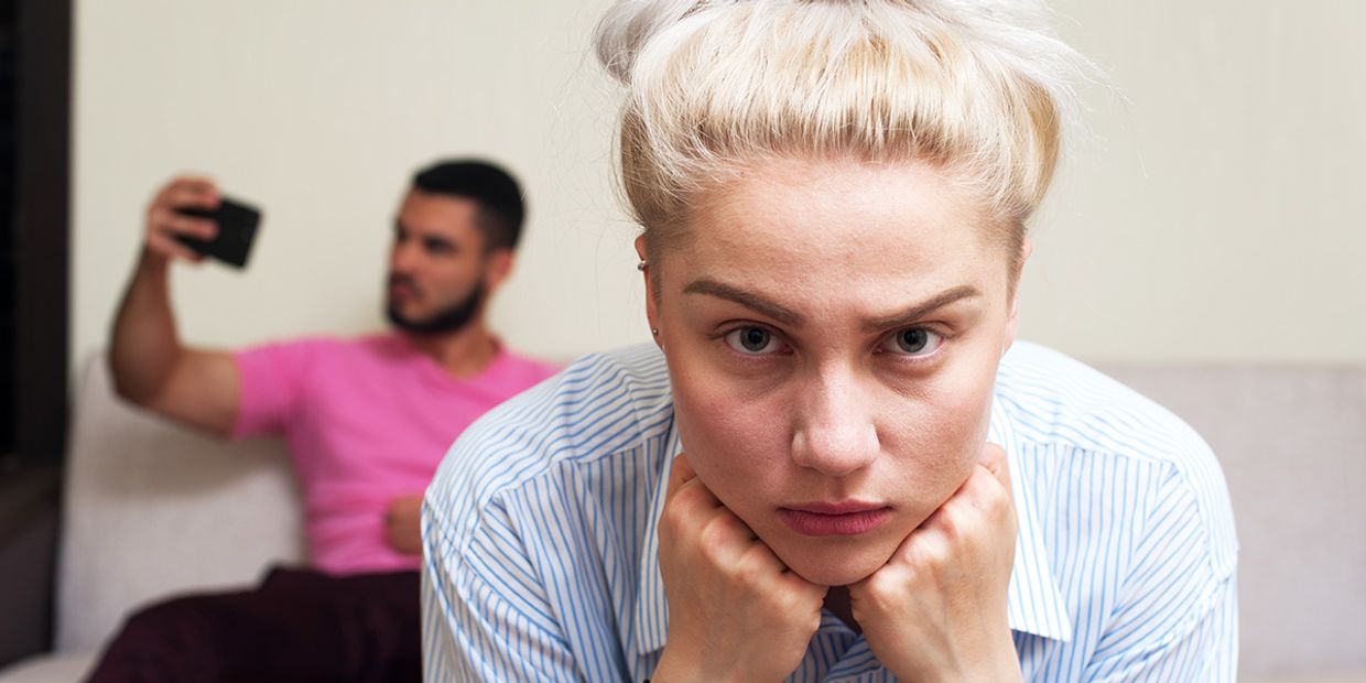 Emotionally strained couple during a breakup, reflecting on thoughts. The male partner is looking at his phone.