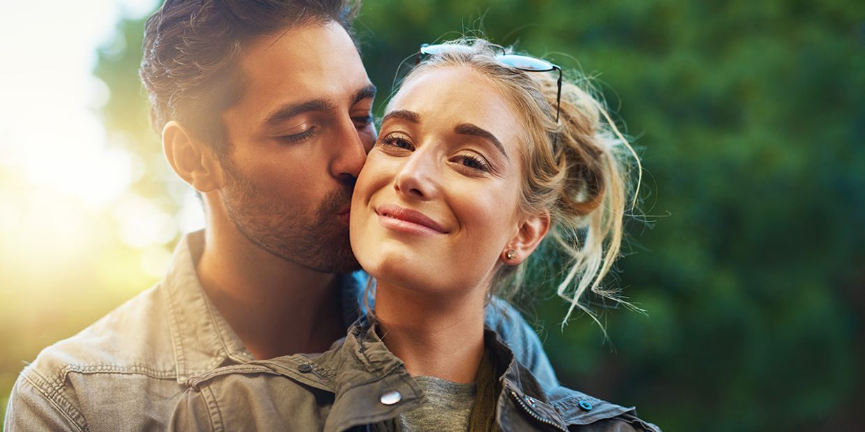 A young couple in love, embracing each other outside.