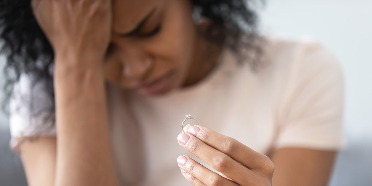 Woman holding an engagement ring, reflecting on her breakup emotions.