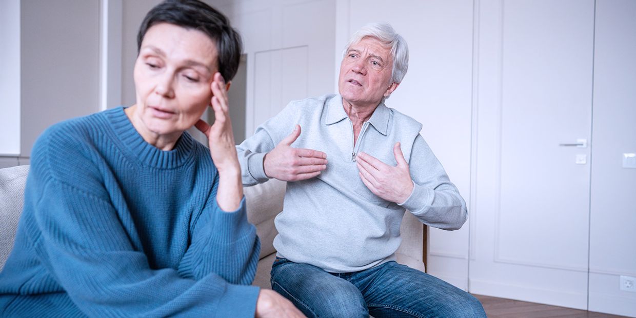 An older couple, sitting in their living room, looking very stressed.