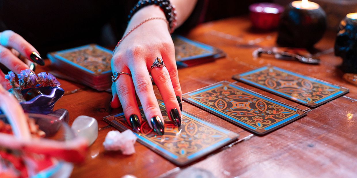 A tarot reader with long black nails, reading a 3 card tarot spread.