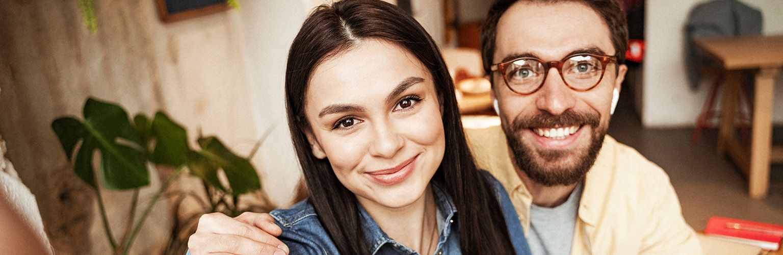 Illustration of a smiling couple sitting together at home, leaning towards each other, and looking into each other’s eyes with a happy relationship, love emotions and connection energy theme.
