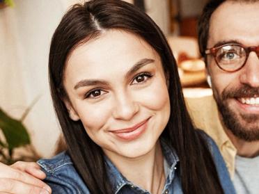 Illustration of a smiling couple sitting together at home, leaning towards each other, and looking into each other’s eyes with a happy relationship, love emotions and connection energy theme.