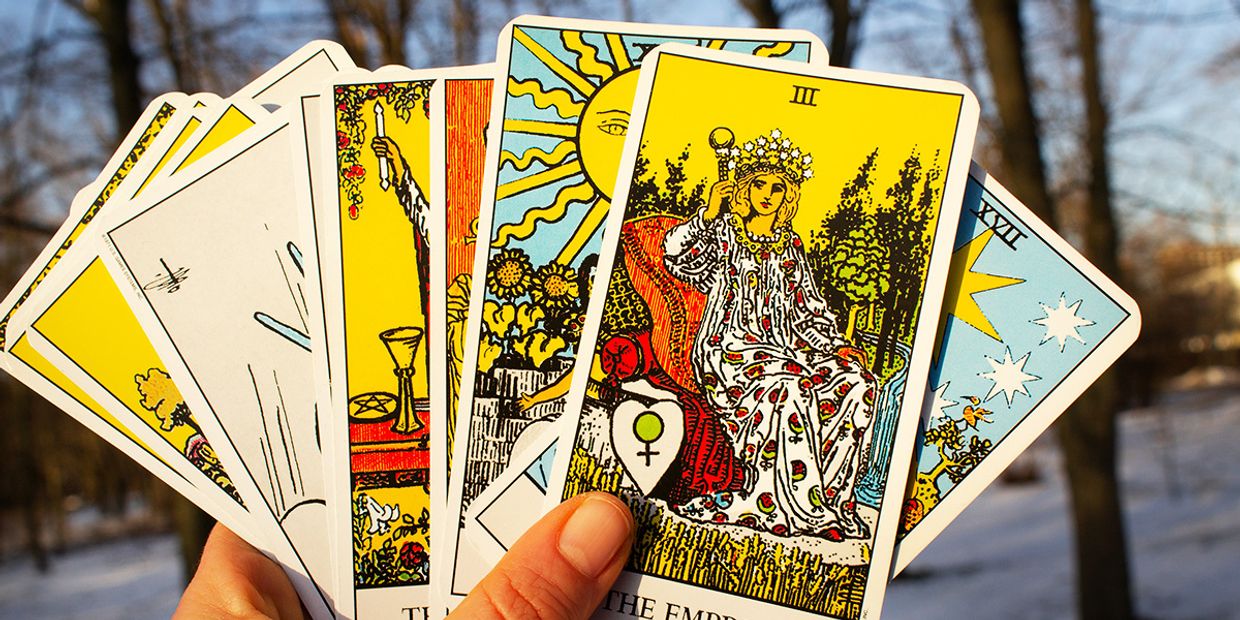 A tarot reader holding a deck of tarot cards, outside in the snow.