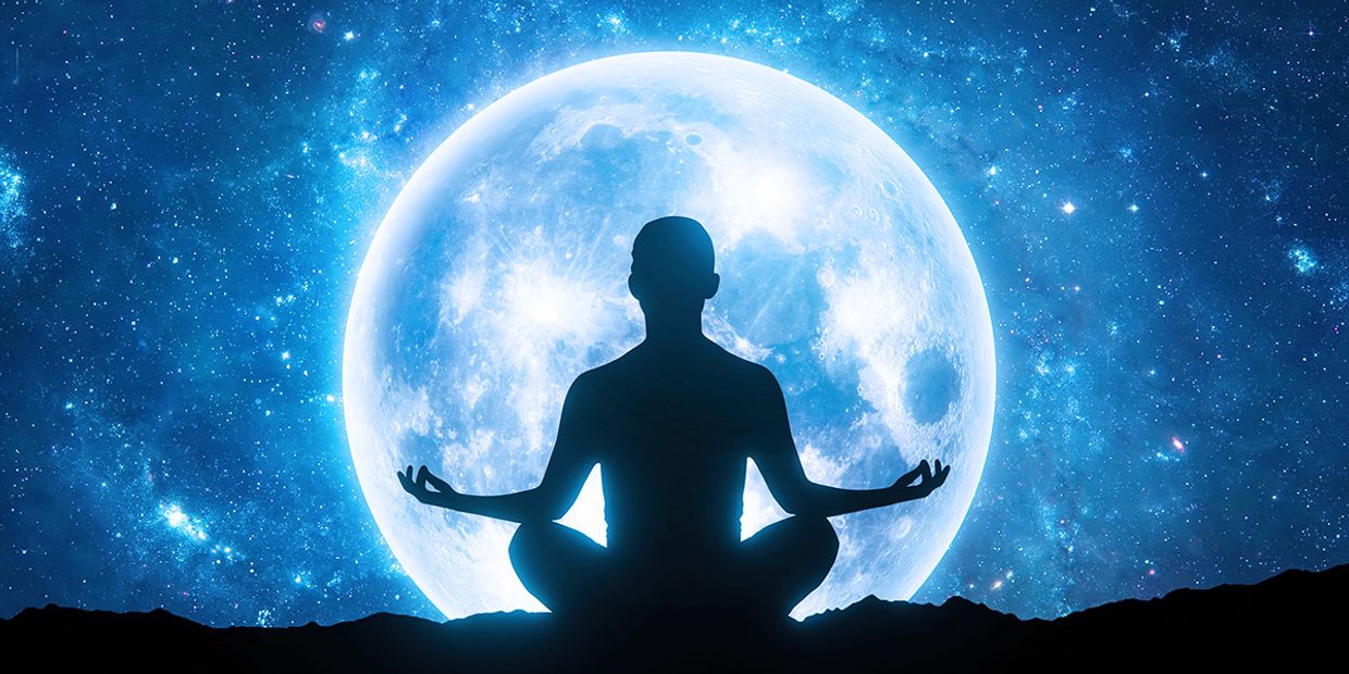 A full moon with a silhouette of a man meditating in front of it.