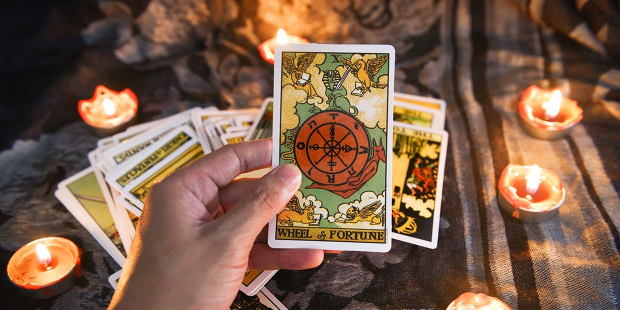 Wheel of Fortune tarot card image against a background of burning candles, representing destiny, life cycles, and powerful spiritual insight.