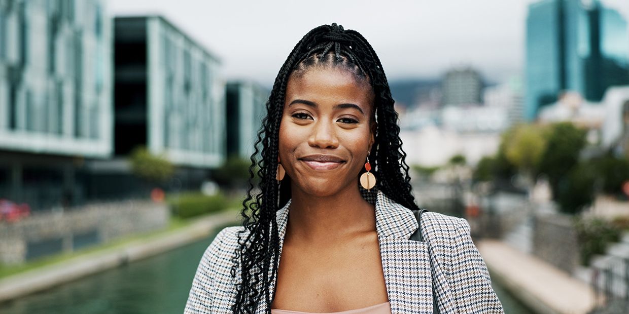 Woman with a confident smile in a modern city street scene, signifying empowerment, clarity, and emotional balance.