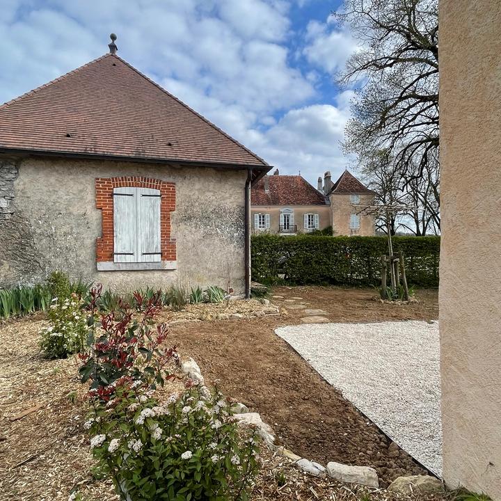 Jardin dans un château de Bourgogne Franche-Comté avec une haie fleurie et bordure en pierre.