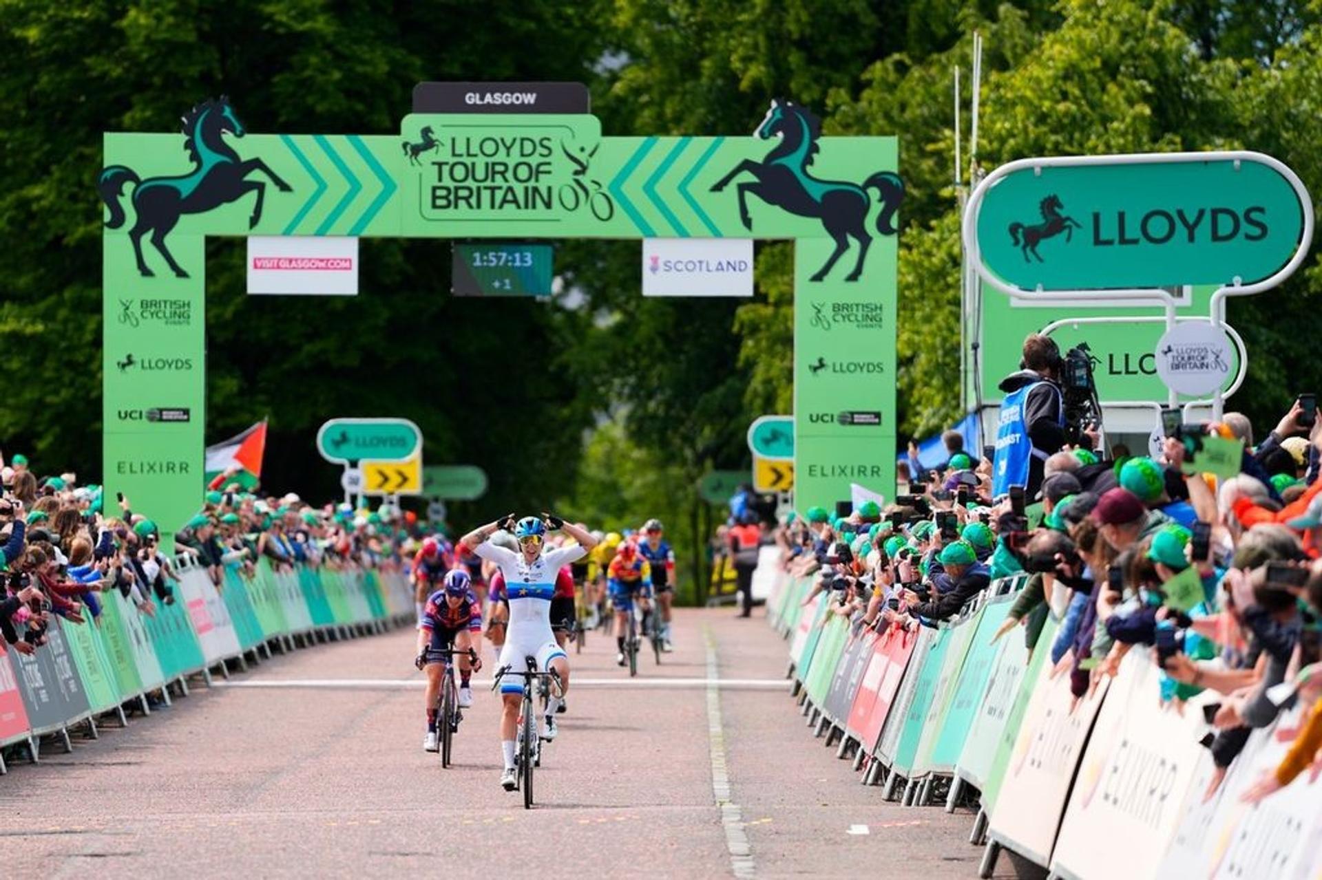 Cyclists race toward the Lloyds Tour of Britain finish in Glasgow as crowds line the road.