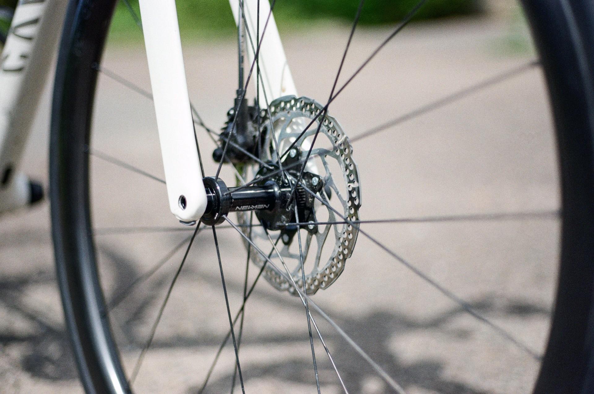 Close-up of a road bike rear wheel and disc brake rotor on a flat pavement path
