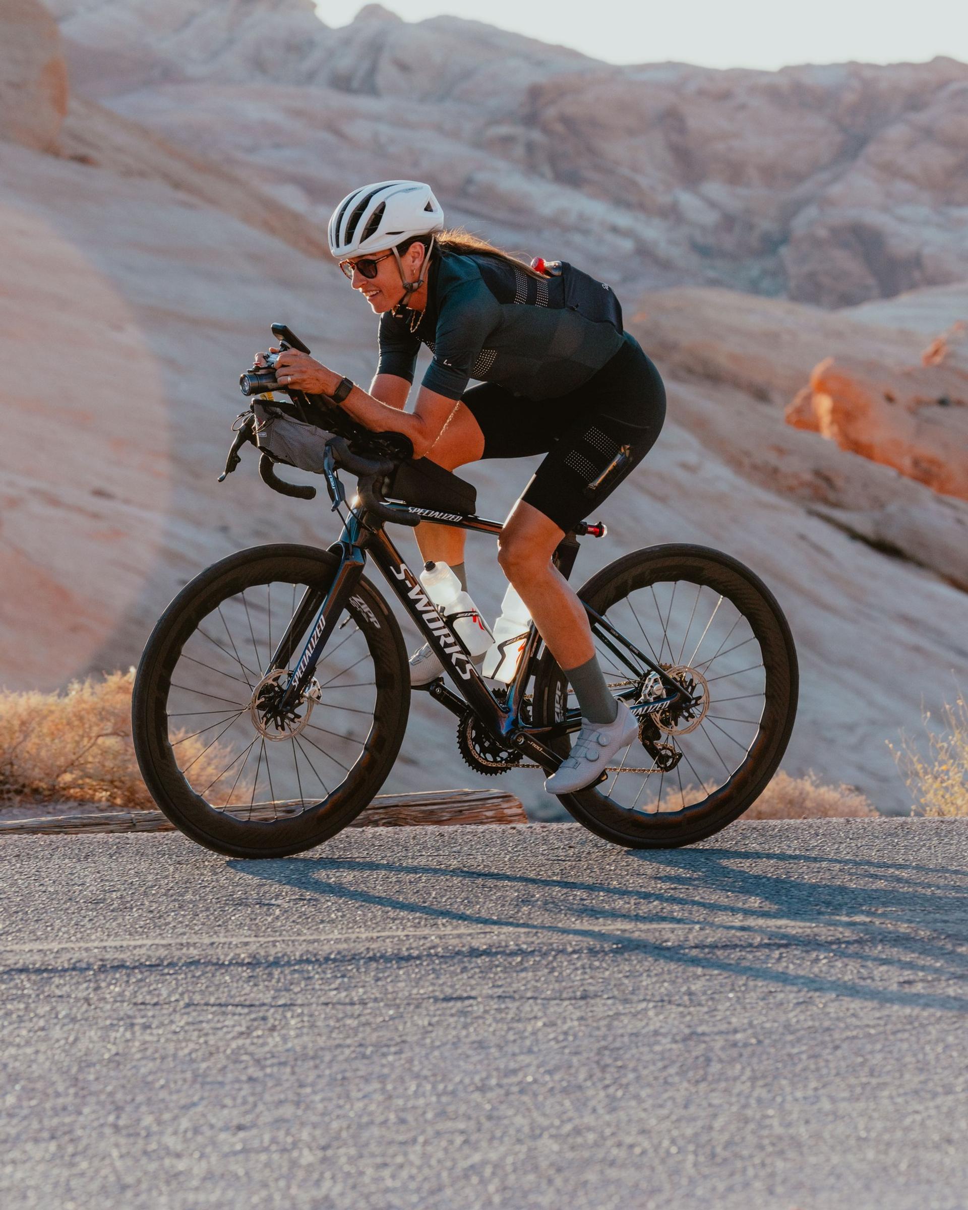 Cyclist leaning into a mountain road climb during a competitive race in rugged rocky terrain.