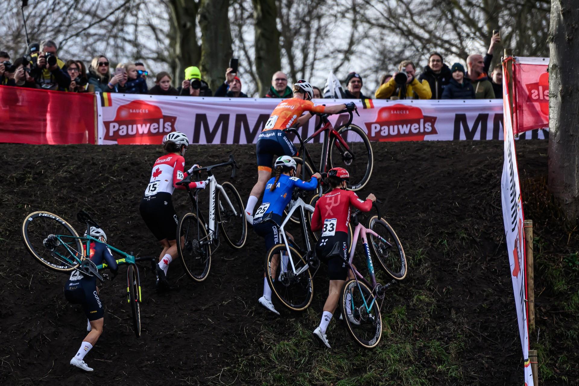 Women racers push bikes up muddy hill at 2026 Hulst Cyclocross Worlds (64 chars)
