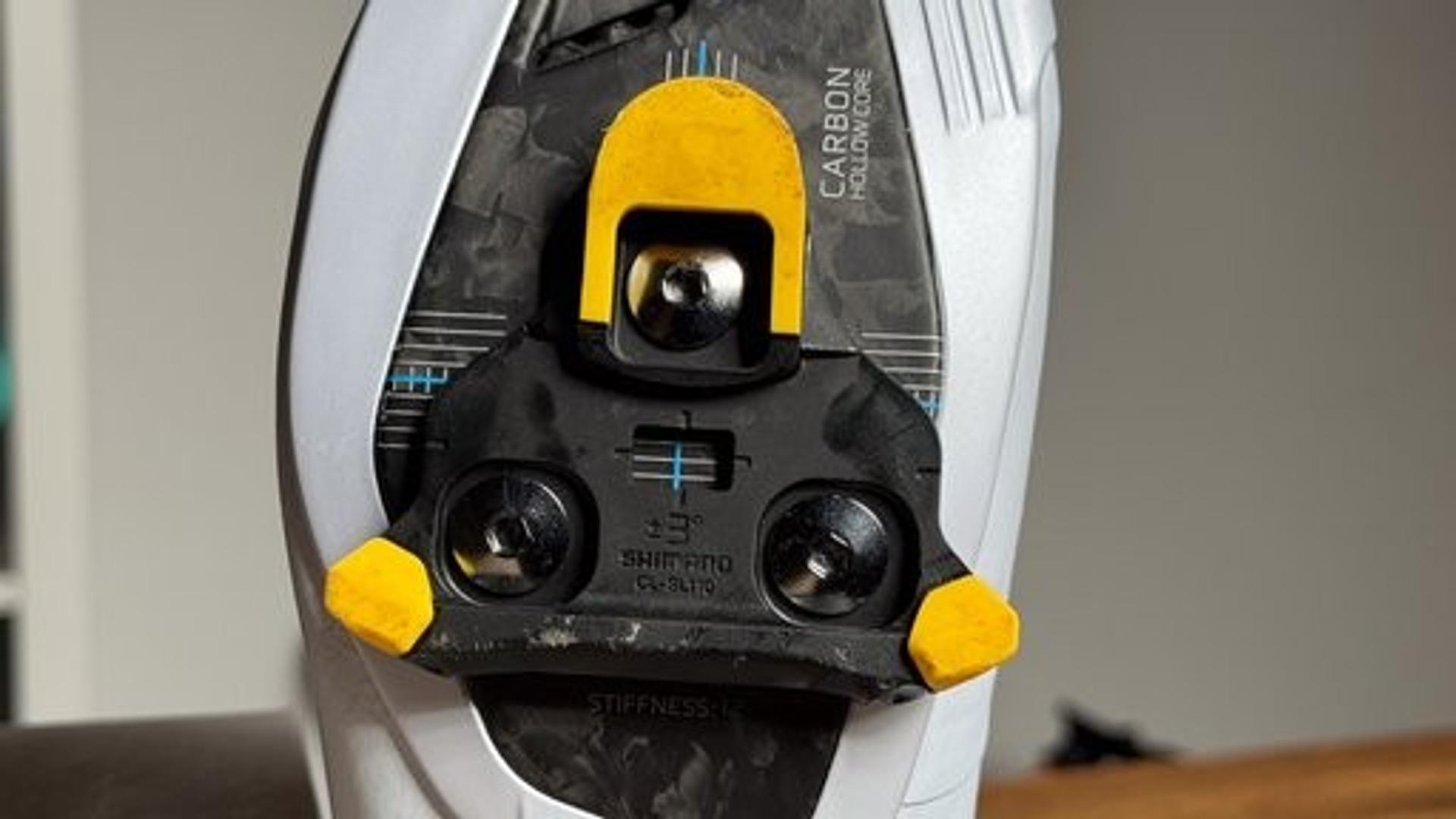Close-up of a Shimano road cycling shoe sole with a yellow SPD-SLR cleat and black mounting hardware